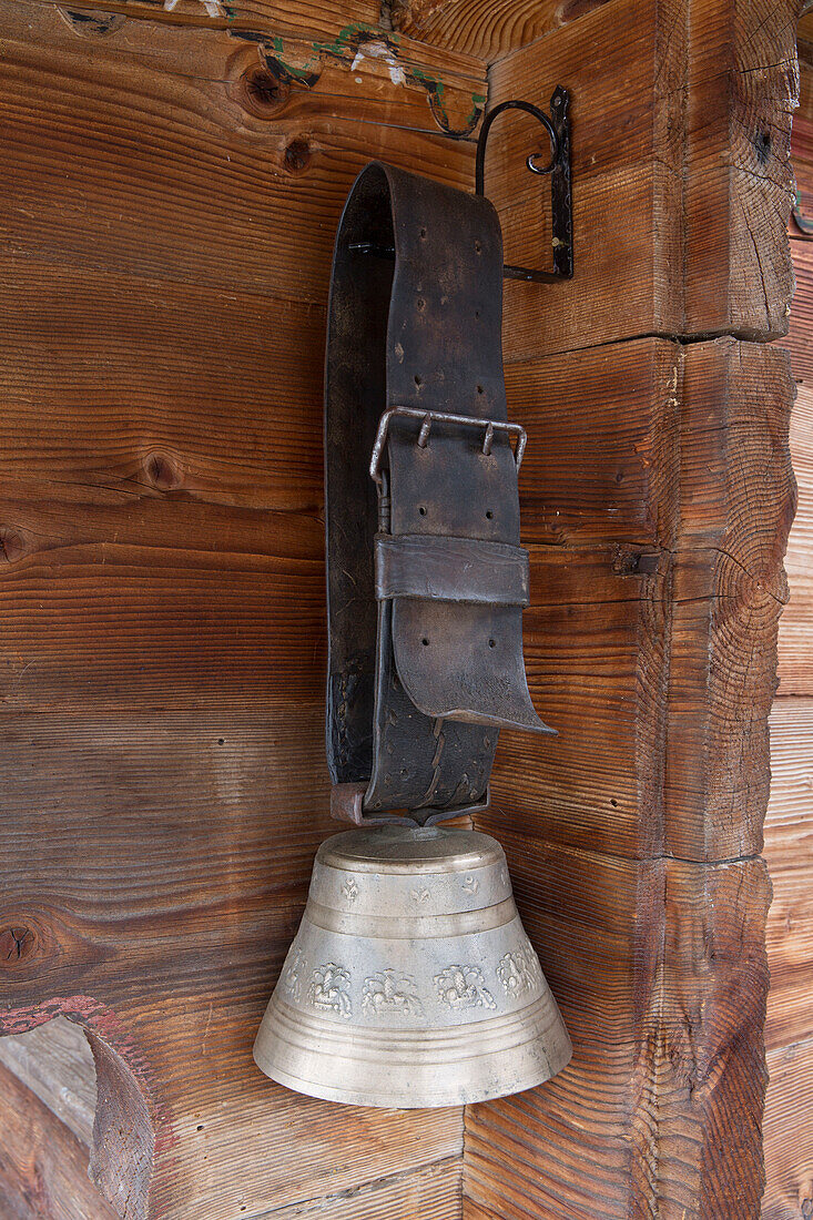 Antike Kuhglocke hängt an einem braunen Lederriemen in einem Bergchalet in Chateau-d'Oex, Waadt, Schweiz