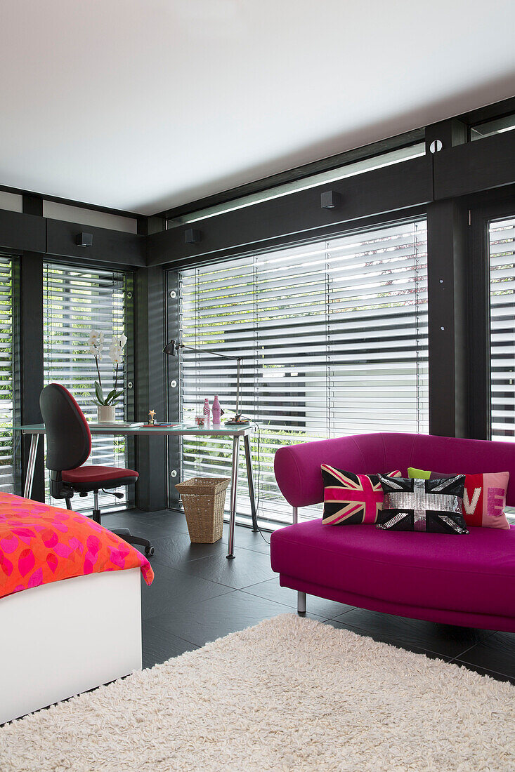 Union Jack cushions on pink sofa with desk and chair in contemporary SW London home, England, UK