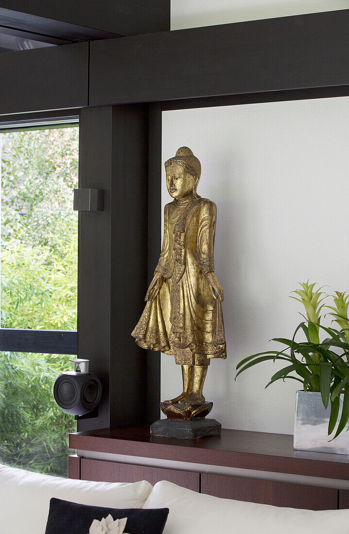 Goldene Buddha-Statue auf einem Sideboard in einem modernen Haus im Südwesten Londons, England, Vereinigtes Königreich