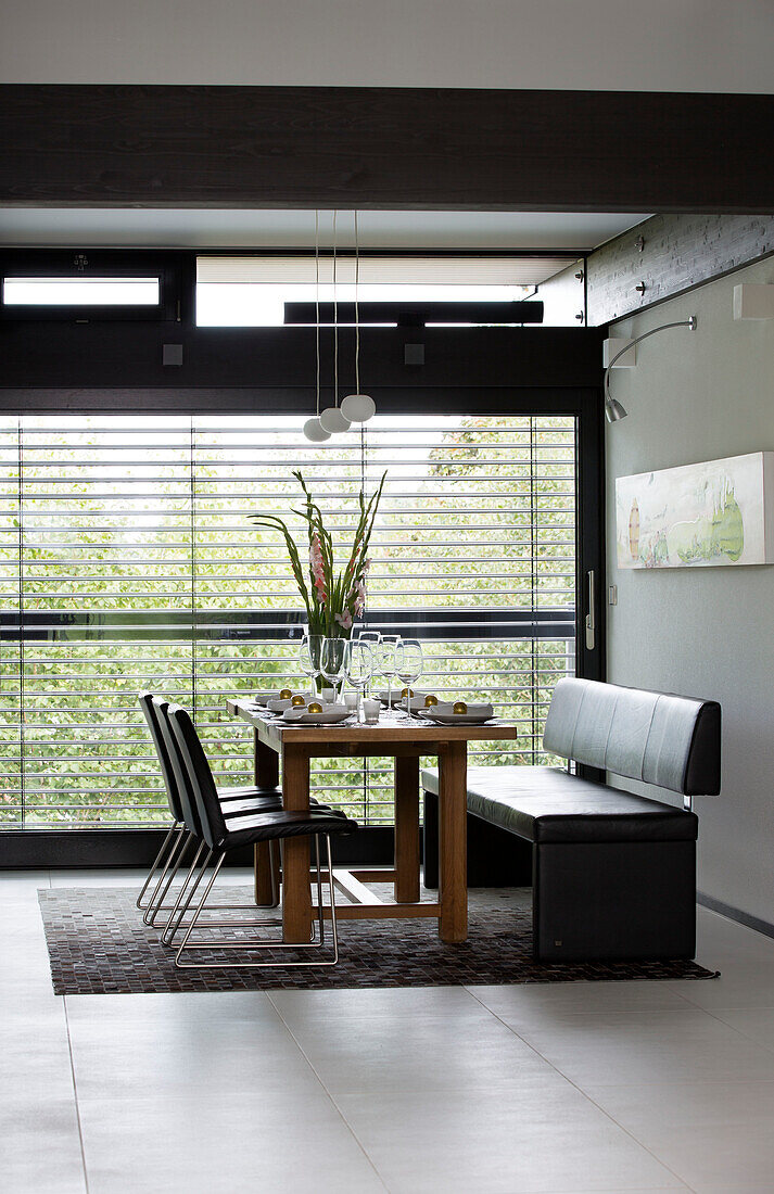 Leather bench seat and chairs at dining table in window of contemporary SW London home, England, UK