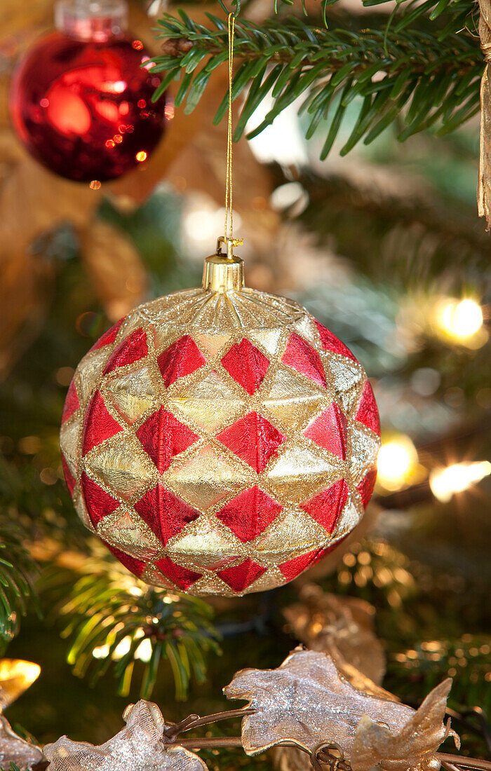 Gold and red bauble hangs on Christmas tree in Chilterns home, England, UK