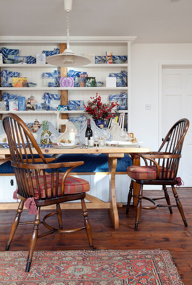 Tartan seat cushions on wooden chairs in dining room with open shelves in Chilterns home, England, UK