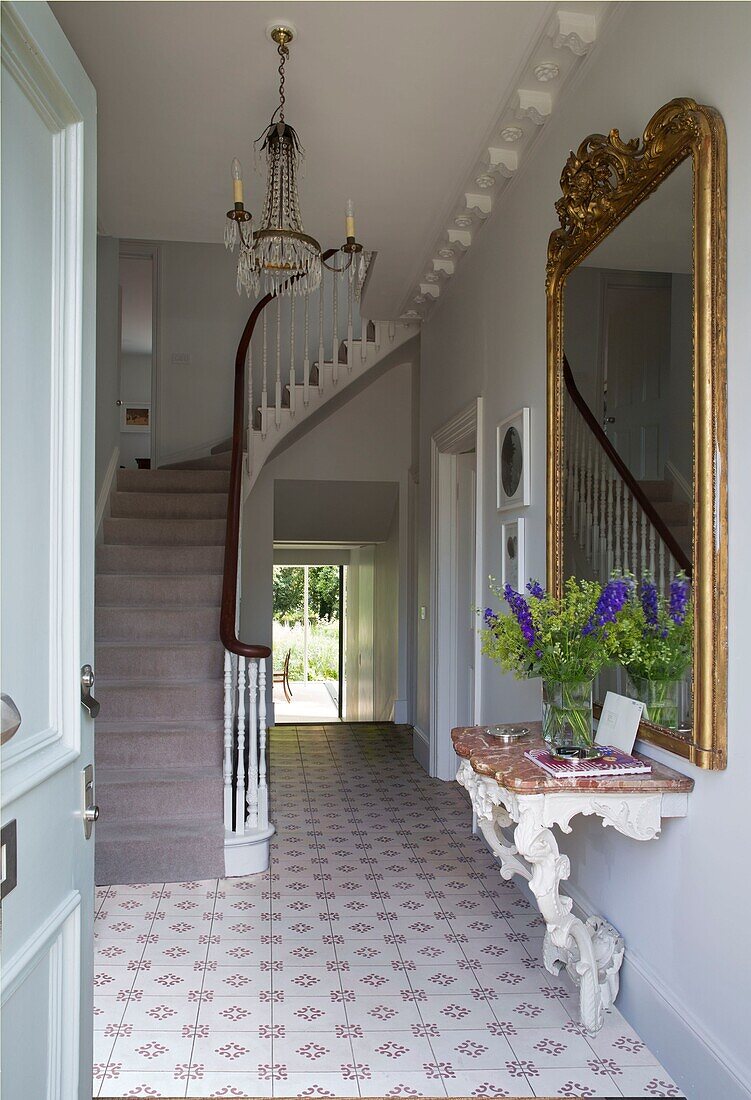 Large gilt framed mirror with coir matting in staircase hallway of Oxfordshire home England UK