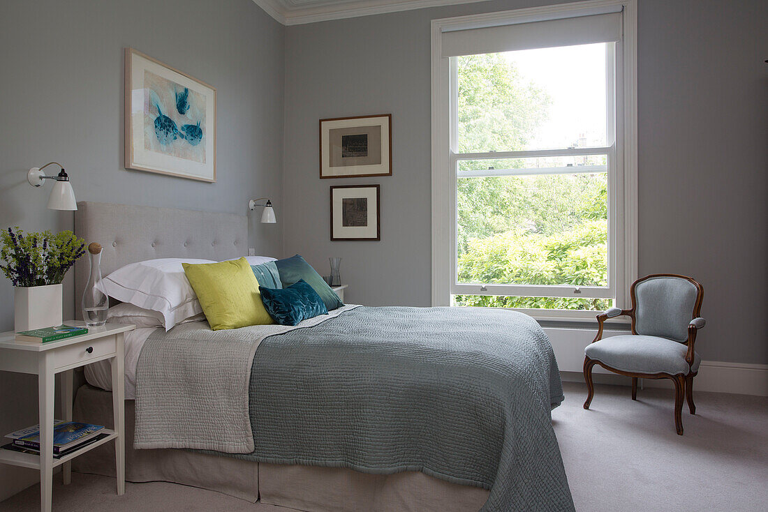 Cut flowers on bedside in double bedroom with large window Oxfordshire home England UK