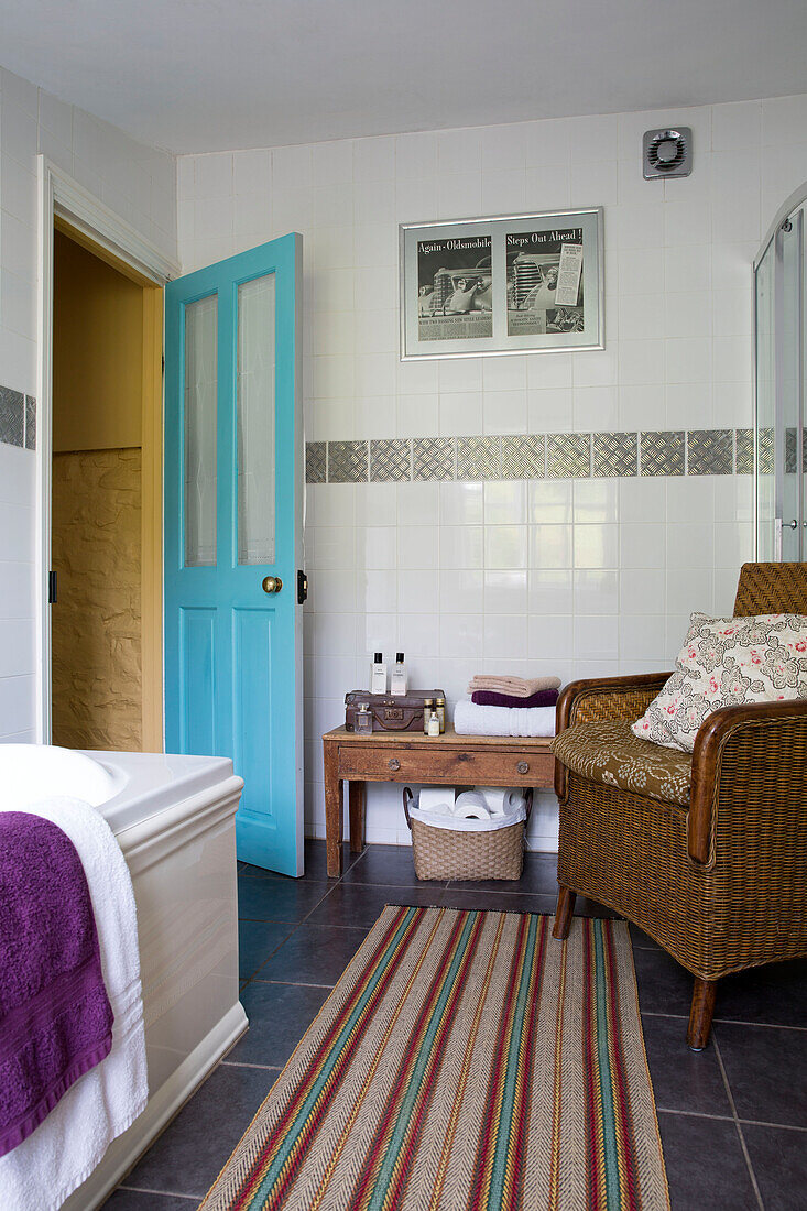 Striped bathmat and wicker chair in tiled bathroom of Ceredigion cottage Wales UK