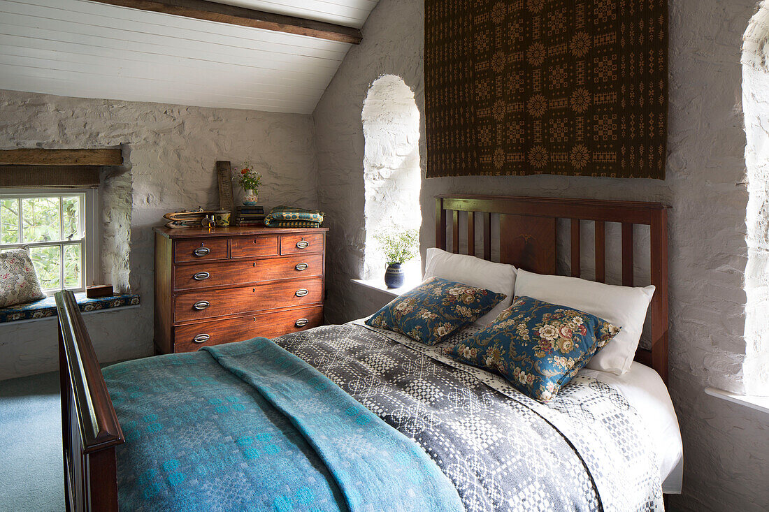 Doppelbett und Wandbehang mit Holzkommode in einem Cottage in Ceredigion, Wales, UK