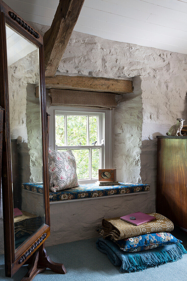 Vintage mirror beside window seat in whitewashed bedroom in Ceredigion cottage Wales UK