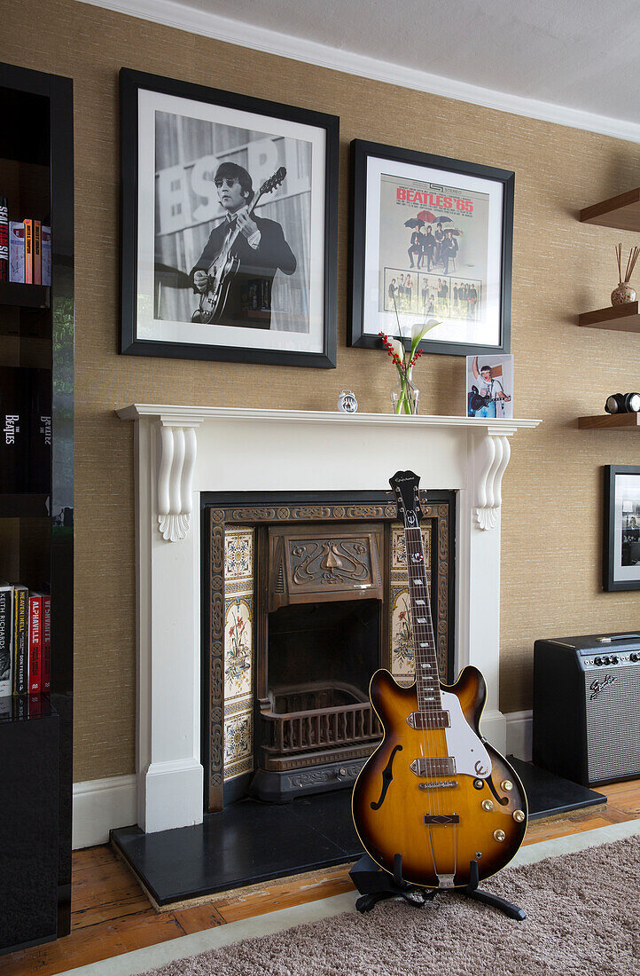 Elektrische Gitarre vor einem Kamin mit gerahmten Drucken in einem Haus in Berkshire, England, UK