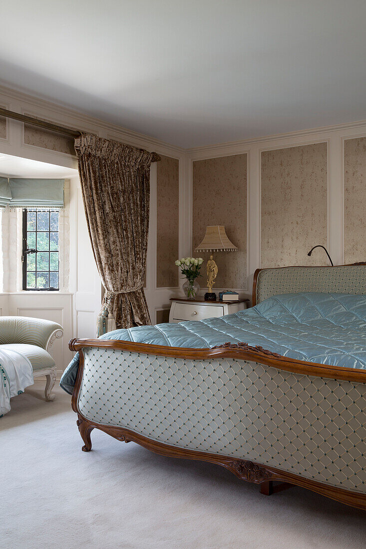 Footboard of kingsize bed with curtains in bedroom detail of London home, UK