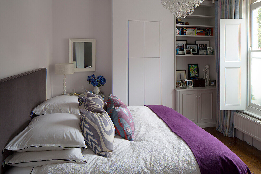 Lila Decke auf einem Doppelbett mit eingebauten Ablageflächen in einem Londoner Stadthaus, England, Vereinigtes Königreich