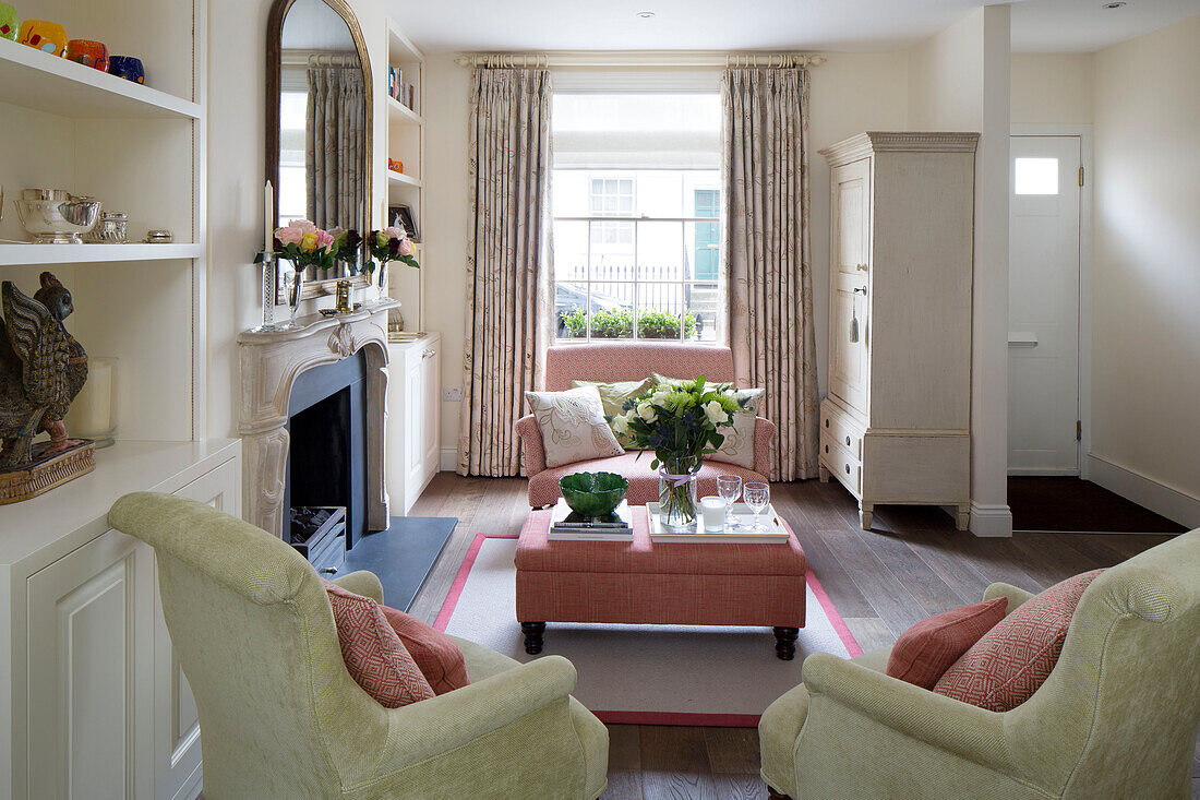 Cut roses on pink ottoman in living room with sash window in London townhouse, England, UK