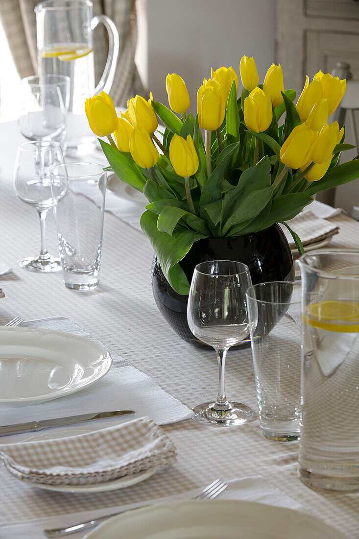 Gelbe Tulpen mit Glaswaren auf Esstisch in britischem Bauernhaus