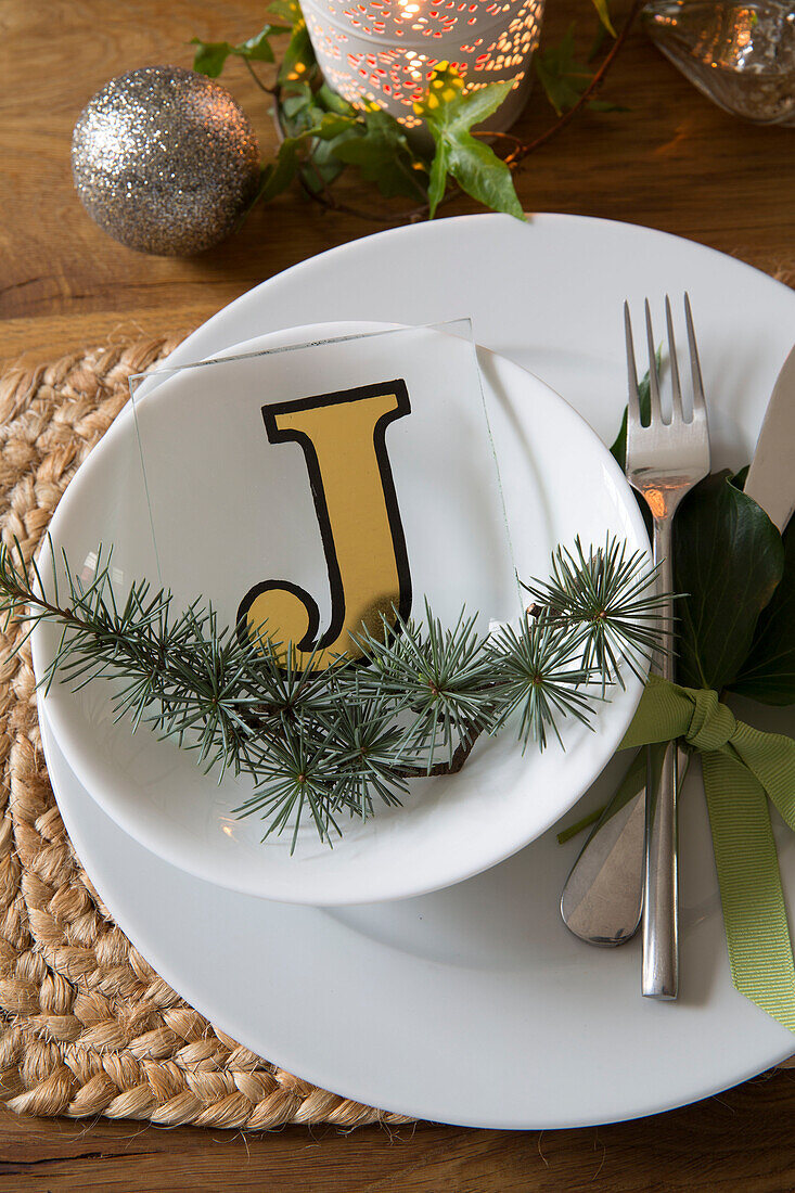 Letter 'J' with pine needles on bowl at place setting in London home, England, UK