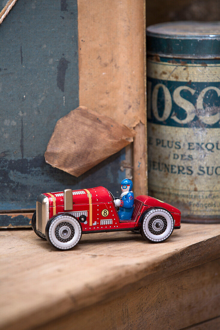 Spielzeugkarte und Aufbewahrungszinke mit altem Bilderrahmen auf Holzregal in französischem Bauernhaus