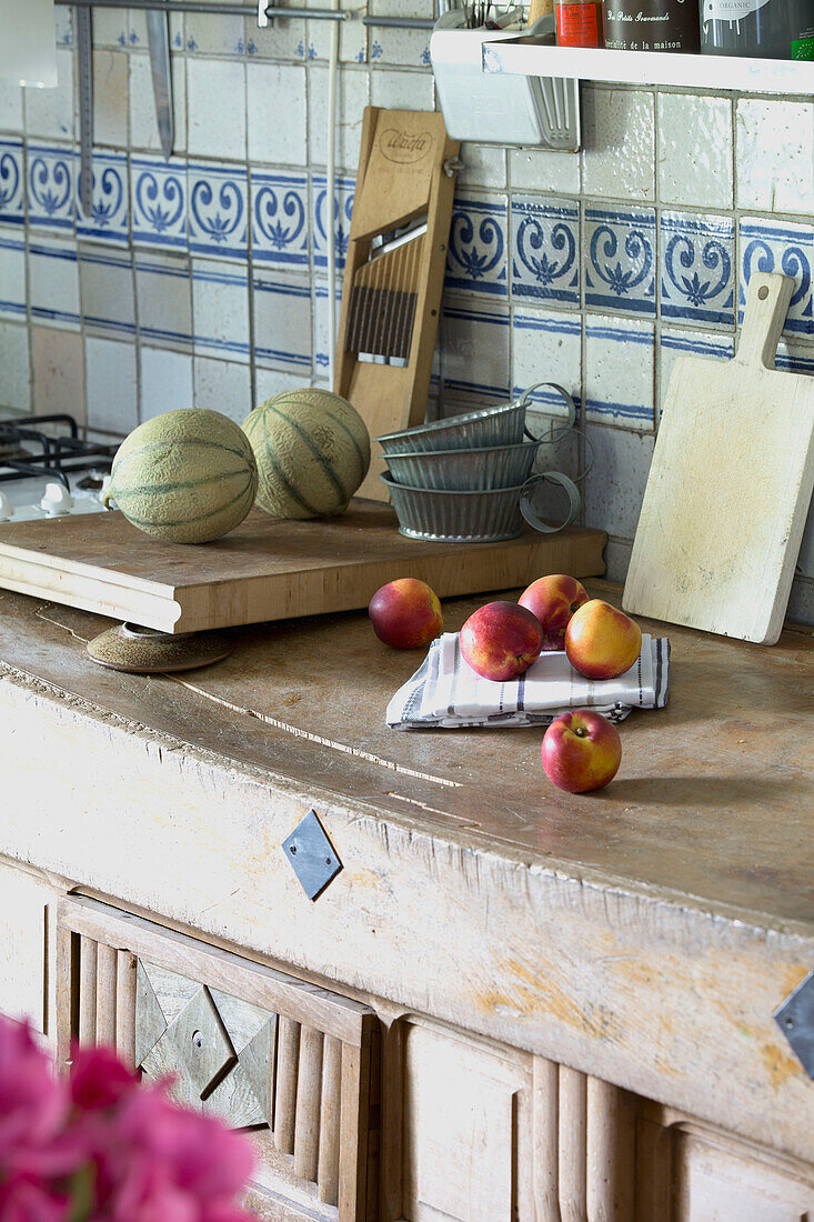 Vintage-Küchengeschirr und Obst auf einer geschnitzten Werkbank in einer französischen Bauernhausküche