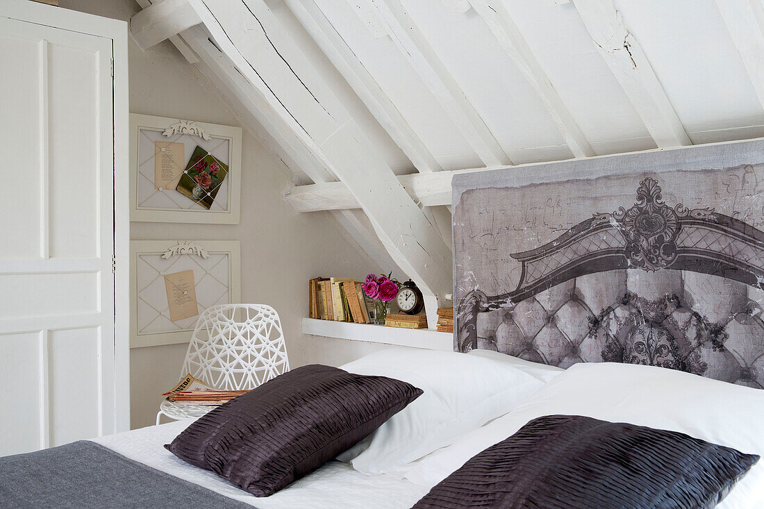 Trompe l'oeil headboard with framed artwork and chair at bedside in French farmhouse