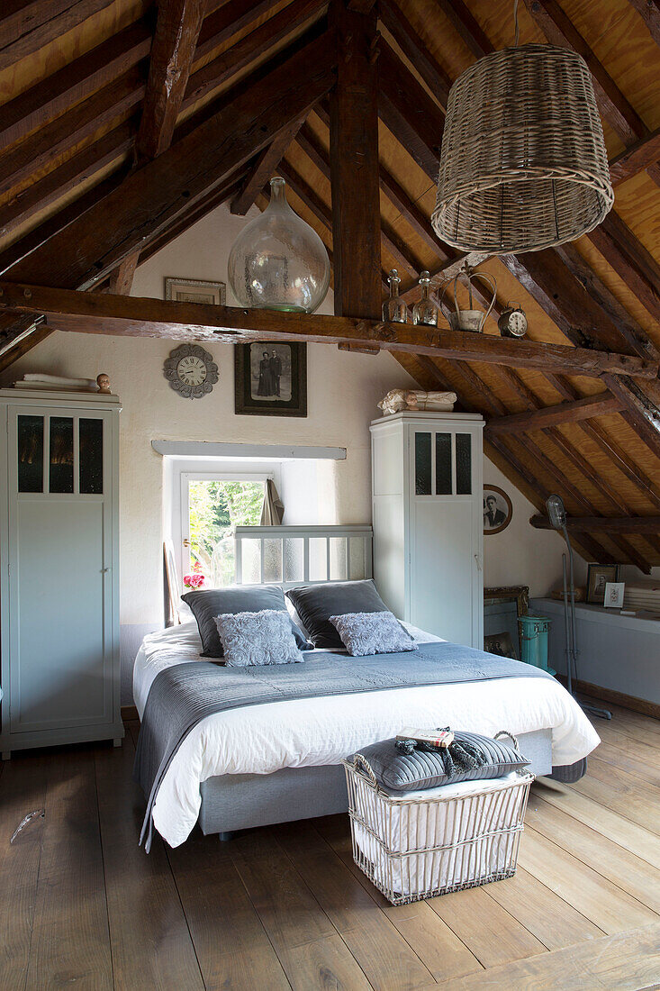 Graues Mobiliar auf einem Doppelbett mit freistehenden Schränken im Schlafzimmer eines Bauernhauses, Frankreich