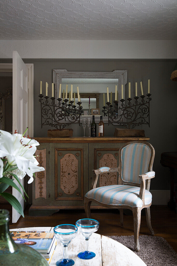 Upholstered chair with painted sideboard and wrought iron candle holder in UK home