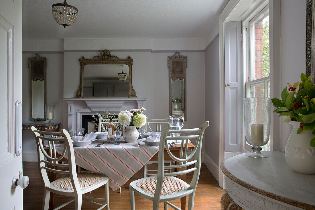 Striped tablecloth on dining table with painted wicker chairs in UK home