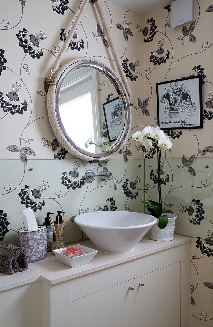 Floral gemusterte Tapete mit Seilspiegel über dem Waschbecken in einem Haus in Großbritannien