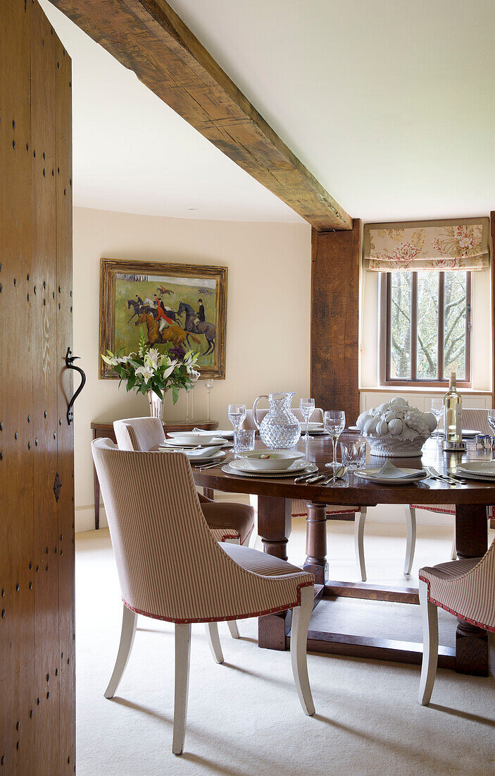 Upholstered dining chairs at place setting  with equestrian artwork in Suffolk farmhouse,  England,  UK