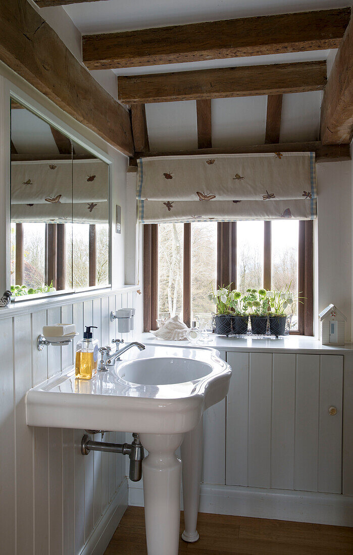 Waschbecken und Spülbecken im weiß getäfelten Badezimmer eines Bauernhauses in Suffolk, England, UK