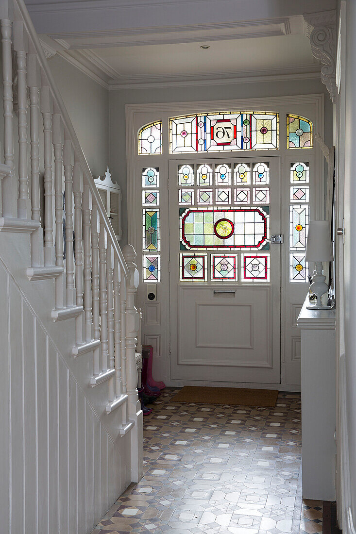 Stained glass front door in white hallway entrance of Hertfordshire home,  England,  UK