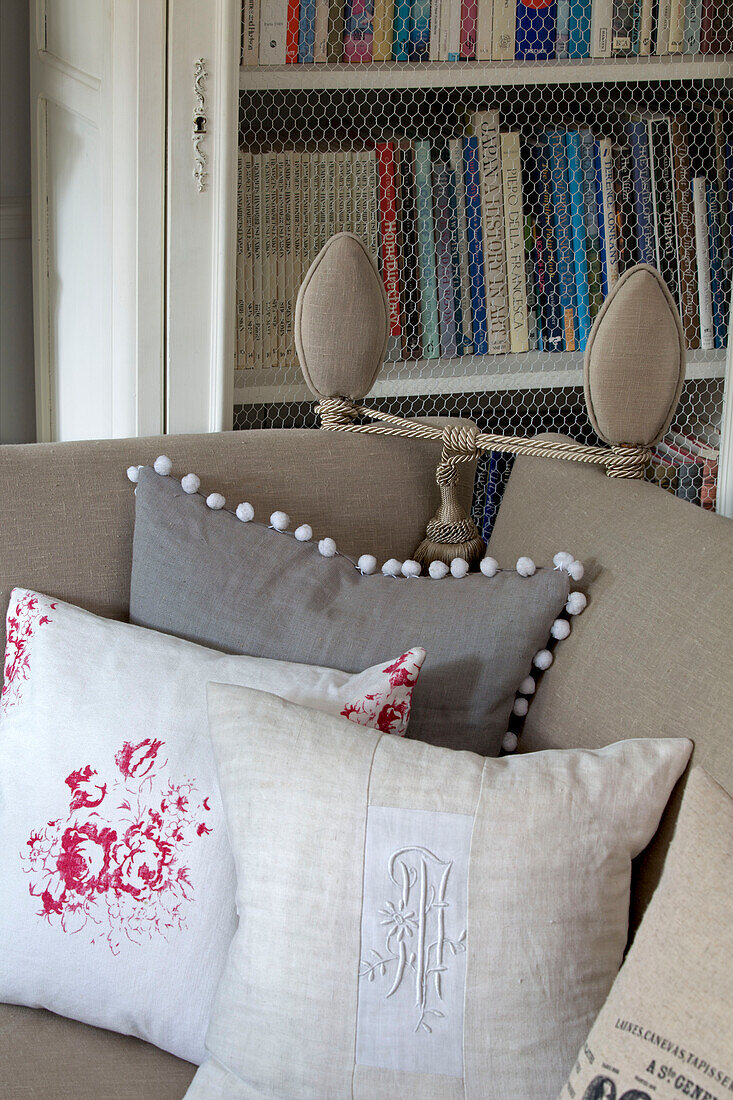Leinenkissen auf Sofa mit Bücherregal im Wohnzimmer in Hertfordshire, England, UK