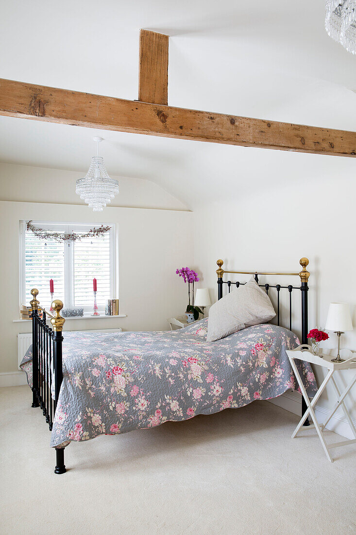 Floral duvet on black metal framed bed under beamed ceiling in Berkshire home,  England,  UK