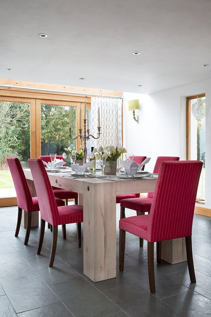 Pink dining chairs at set pale wooden table in Sussex cottage   England   UK