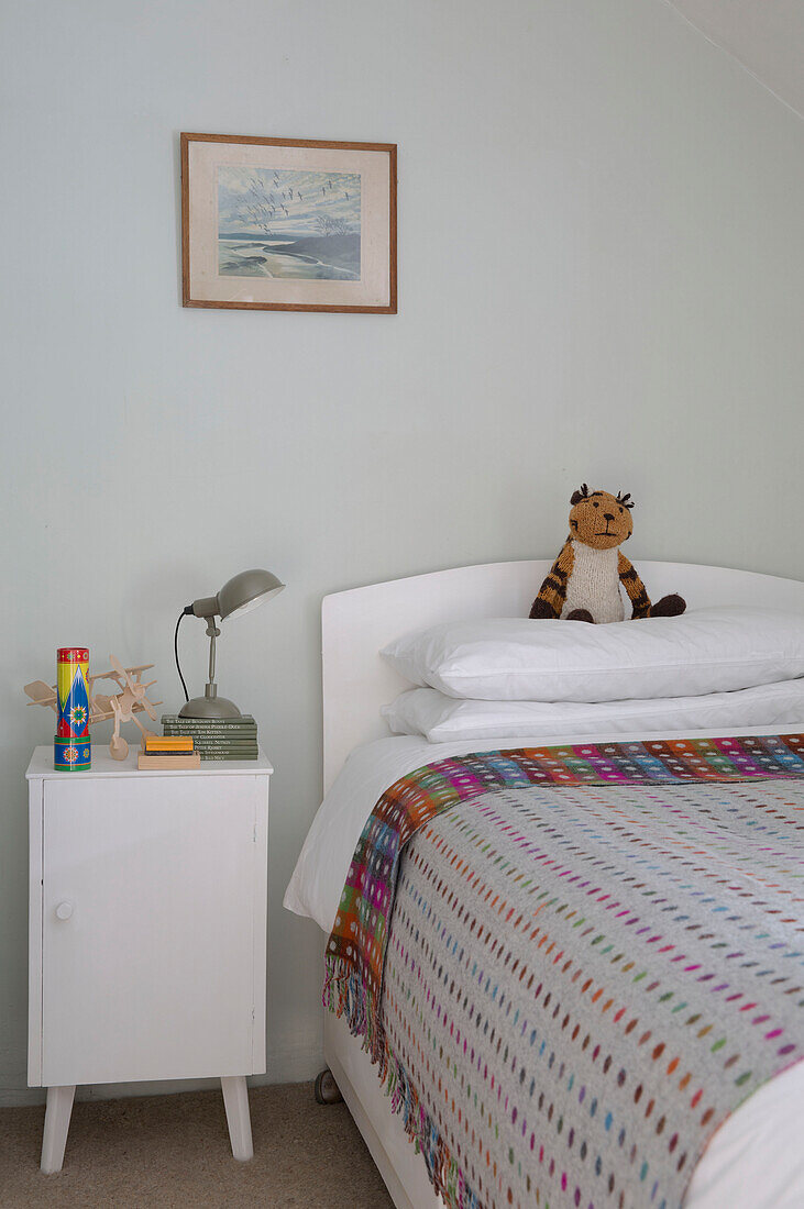 Kuscheltier auf Einzelbett mit gepunkteter Decke und Beistellschrank in Presteigne cottage Wales UK