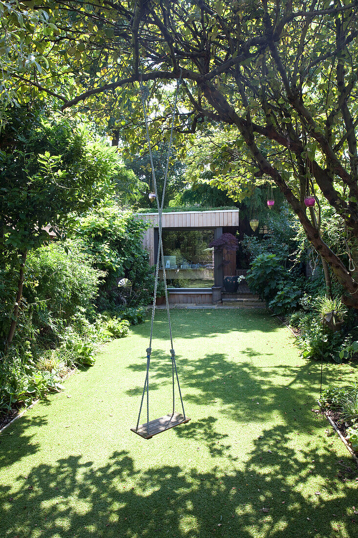 Tree swing in shaded back garden with summerhouse, London, England, UK