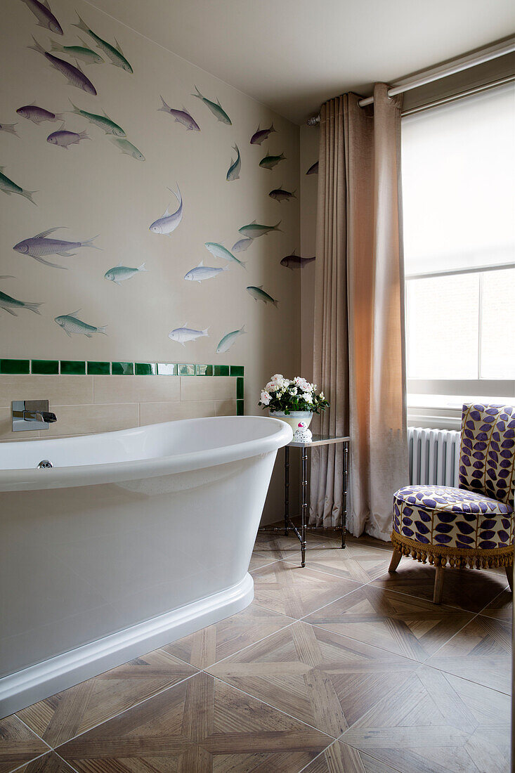 Fische schwimmen an der Wand über einer weißen, freistehenden Badewanne in einem Haus in London, England, Vereinigtes Königreich