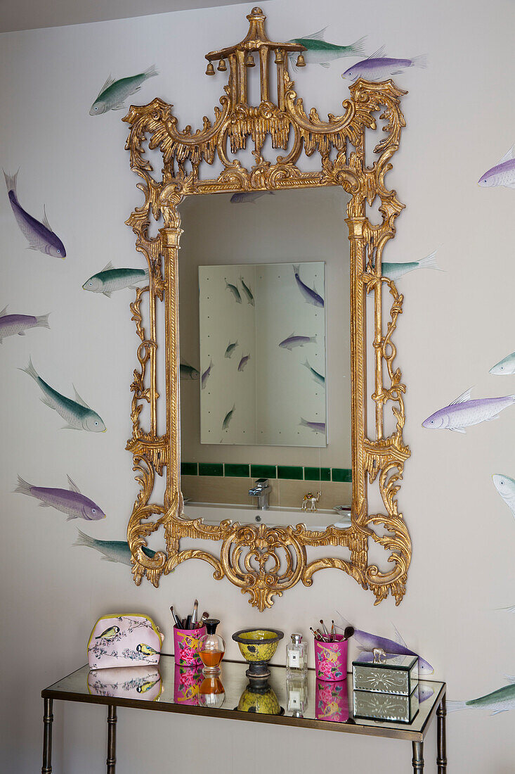 Fische schwimmen an der Wand hinter einem goldgerahmten Spiegel im Badezimmer eines Hauses in London, England, UK