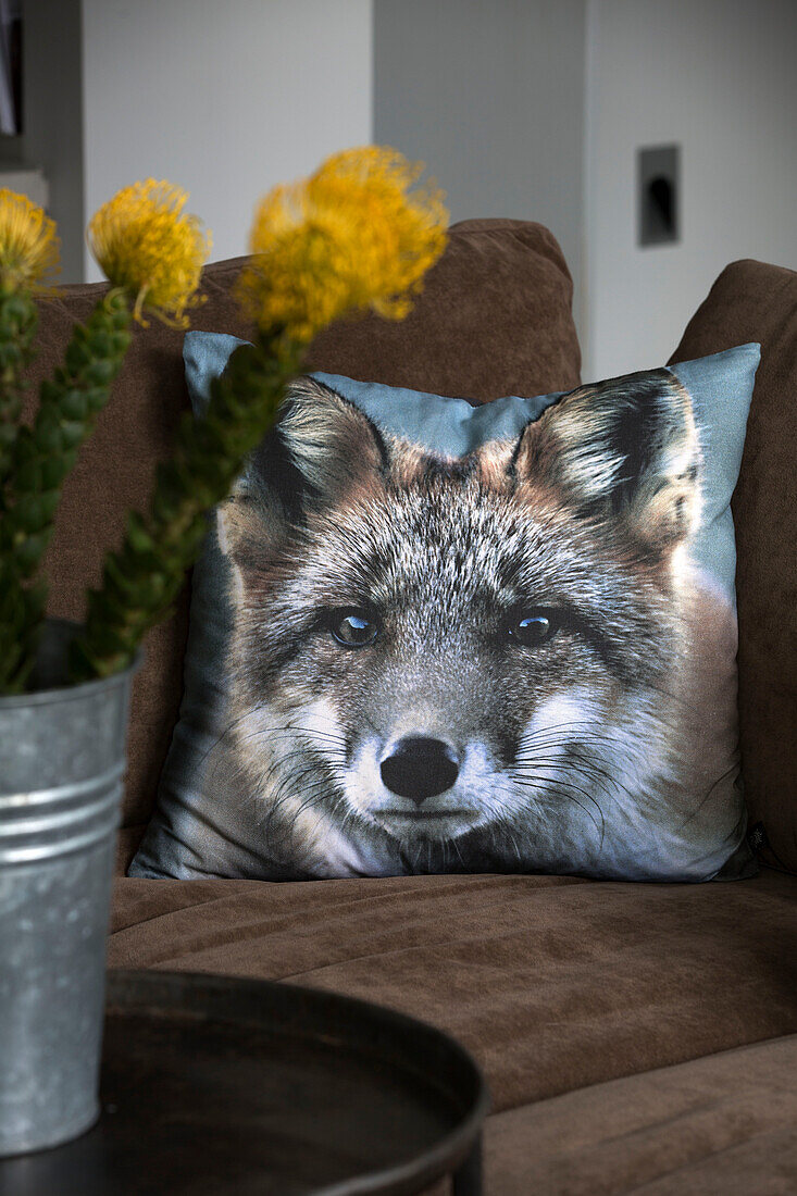 Wolf cushion on brown sofa with cut flowers in contemporary Sussex living room, England, UK