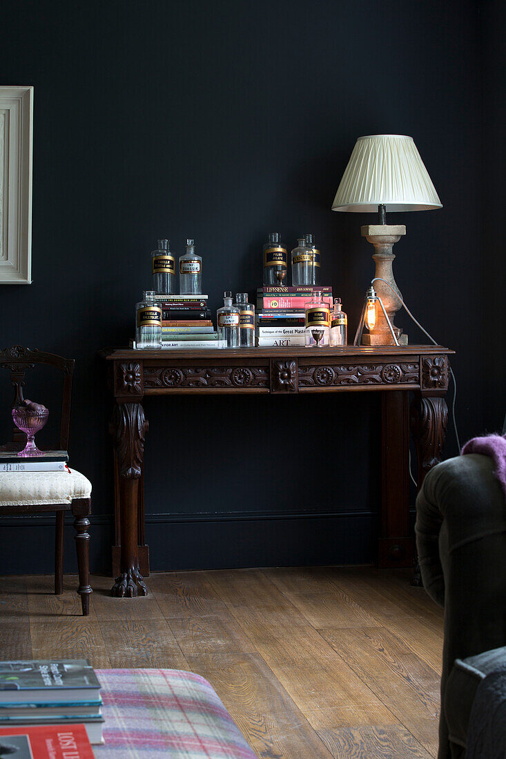 Lampe und Medizinflaschen mit Büchern auf geschnitztem Holztisch in einem Haus in Sussex UK