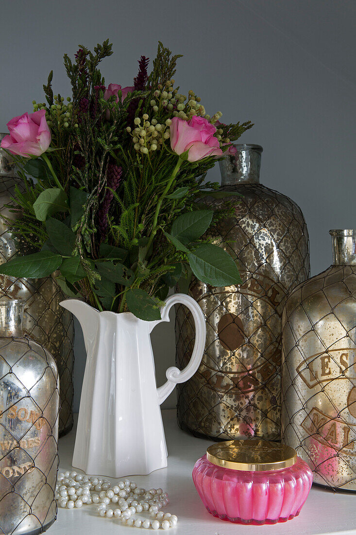 Rosa Rosen mit alten Silberflaschen in einem Haus in Sussex UK