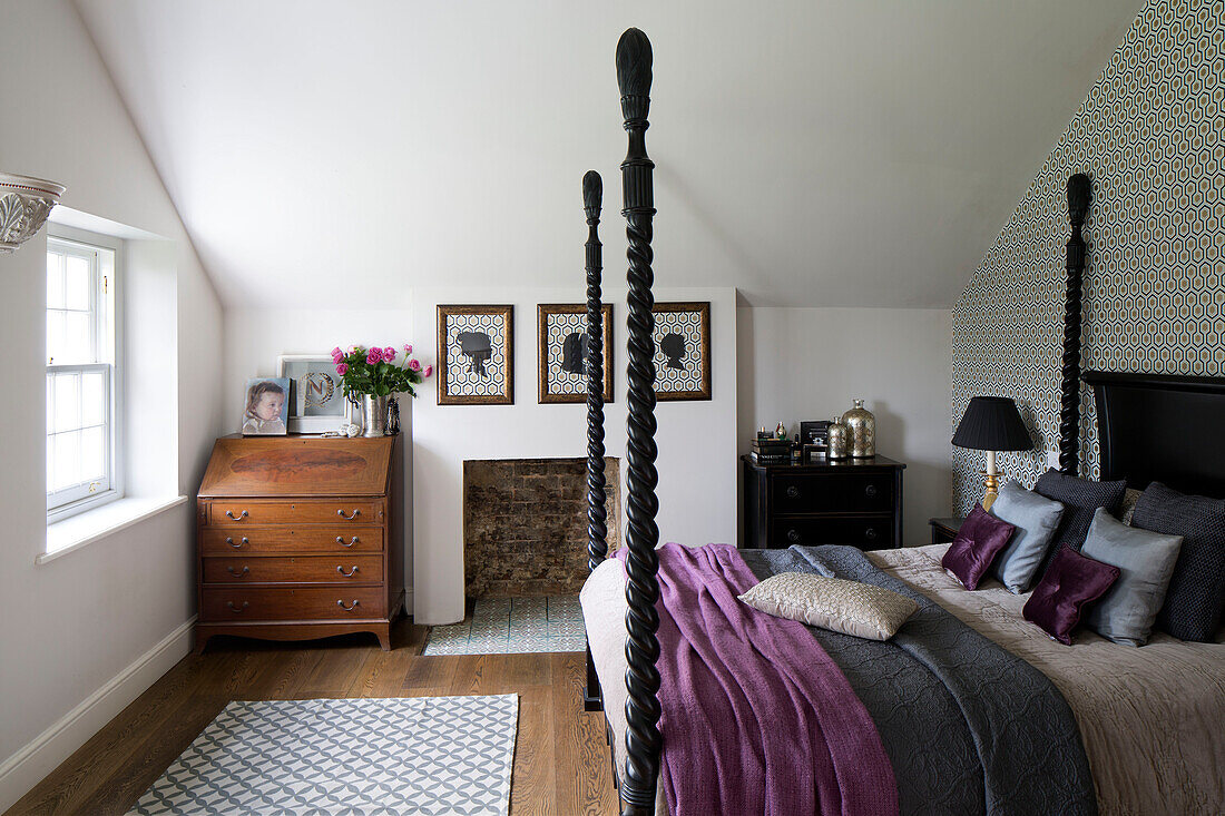 Kamee-Kunstwerke mit Holzkommode und geschnitzten schwarzen Bettpfosten in einem Schlafzimmer in Sussex UK
