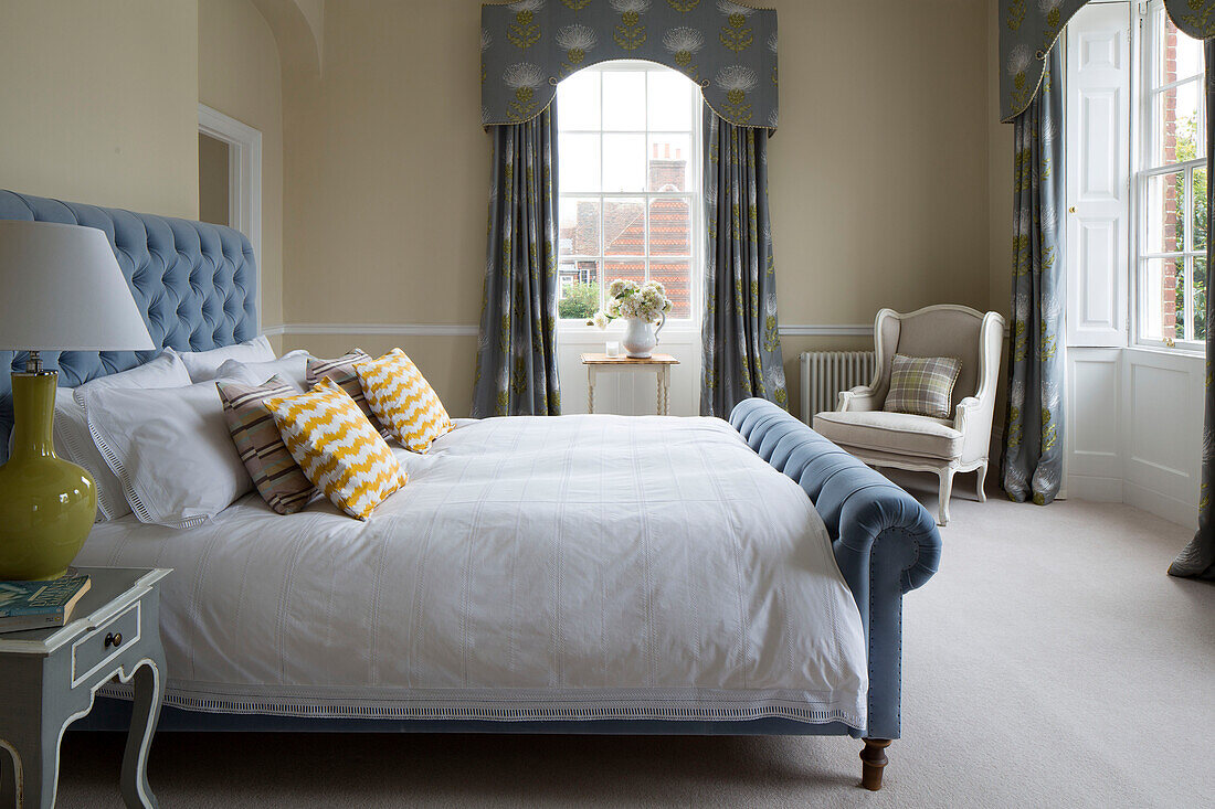 Light blue buttoned double bed and curtain pelmets in Surrey home,  England,  UK