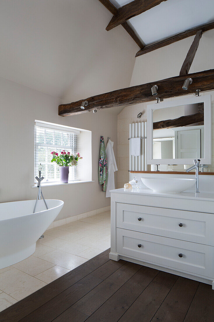 Freistehende Badewanne und Waschbecken in einem zweistöckigen Haus mit Balken in Surrey, England, UK