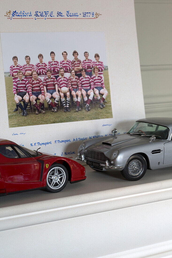 Red and silver collectable cars with photograph of rugby team in Surrey home,  England,  UK