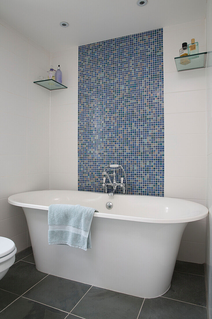 Freistehende Badewanne mit blauem Mosaikspritzschutz in einem Londoner Haus England UK