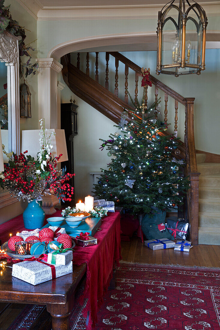 Weihnachtsbaum mit brennenden Kerzen auf einem Tisch im Flur in einem Haus in Sussex, England, Vereinigtes Königreich