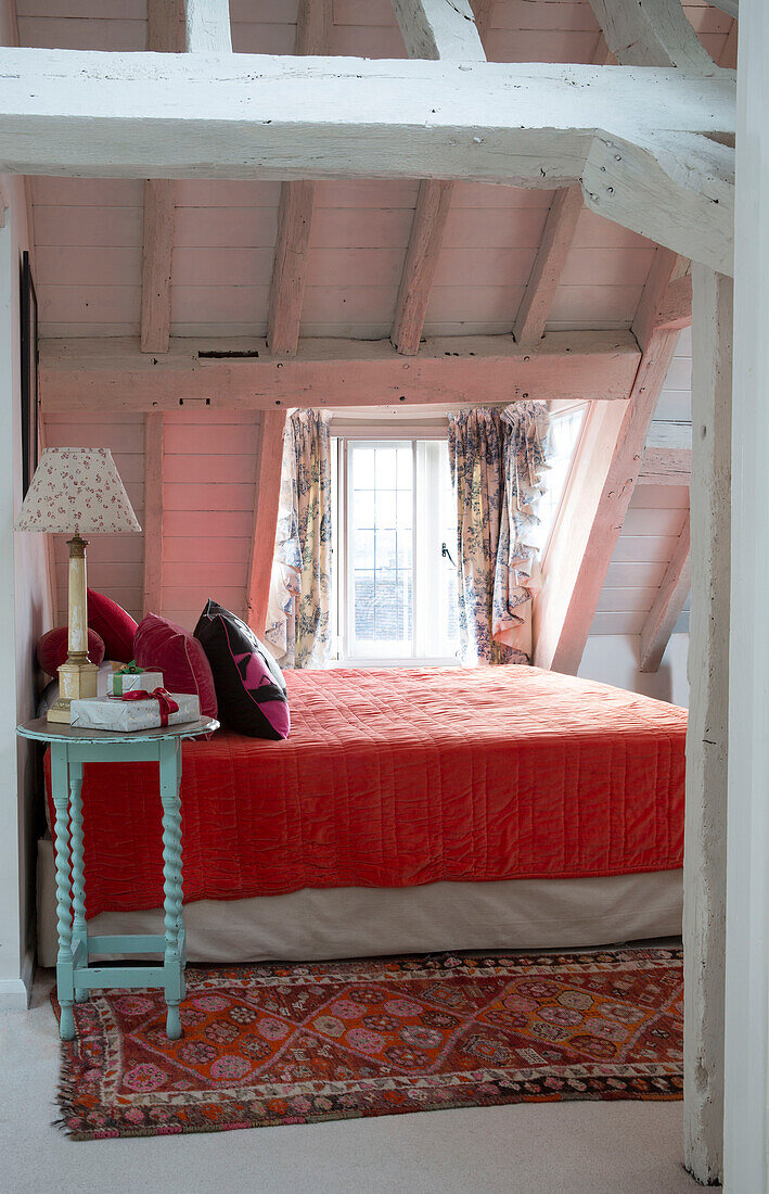 Rote Steppdecke auf einem Doppelbett in einem Schlafzimmer im Dachgeschoss eines Hauses in Sussex England UK
