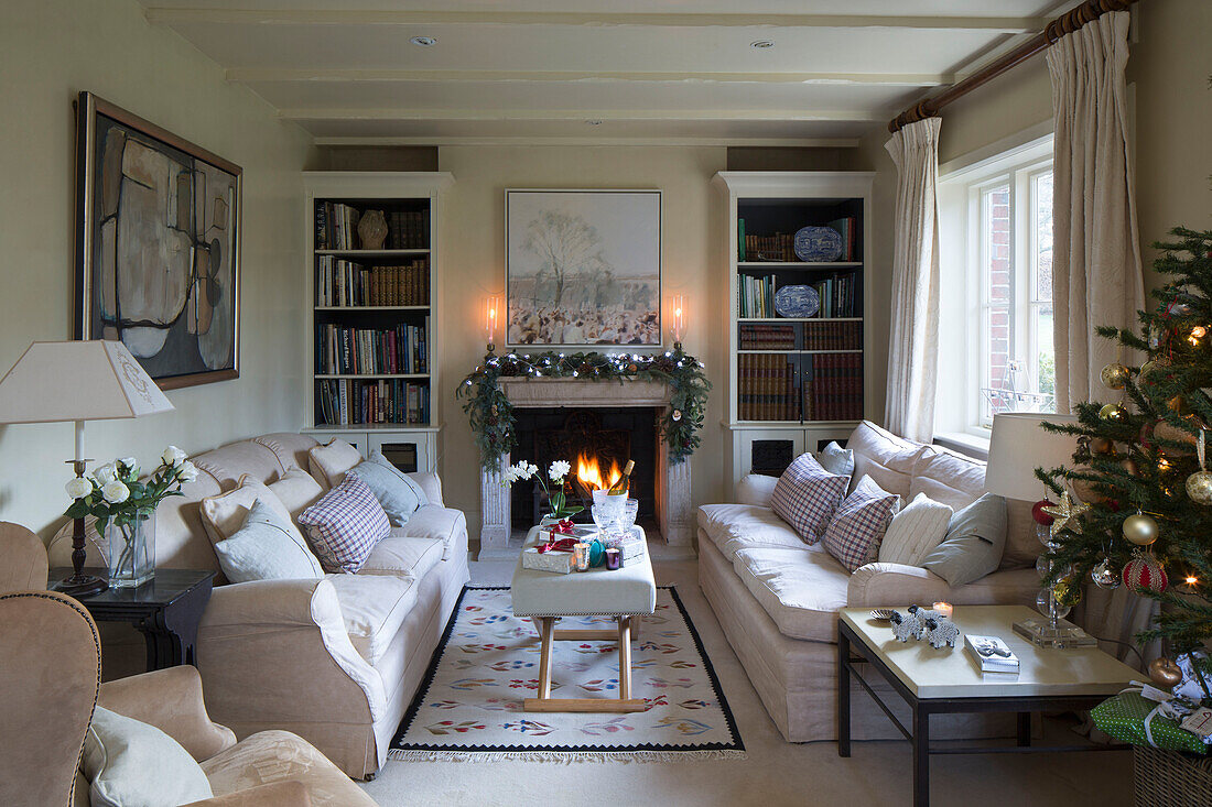Weihnachtsbaum und Girlande über beleuchtetem Feuer im Wohnzimmer von Lymington mit passenden Sofas Hampshire UK
