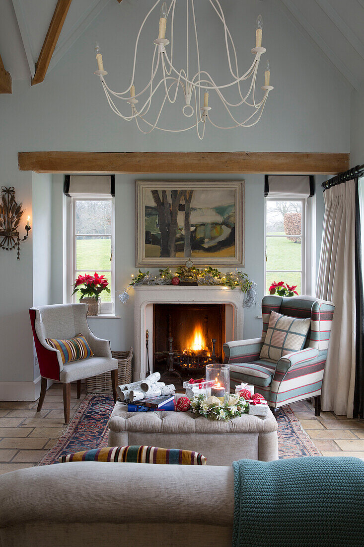 Gepolsterte Sessel am beleuchteten Feuer im Wohnzimmer von Lymington, Hampshire UK