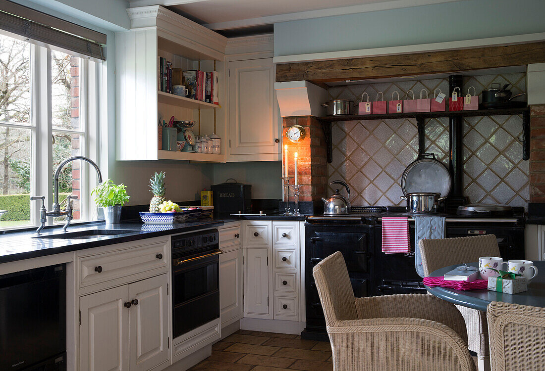Korbsessel in schwarz-weißer Einbauküche in einem Haus in Lymington, Hampshire UK