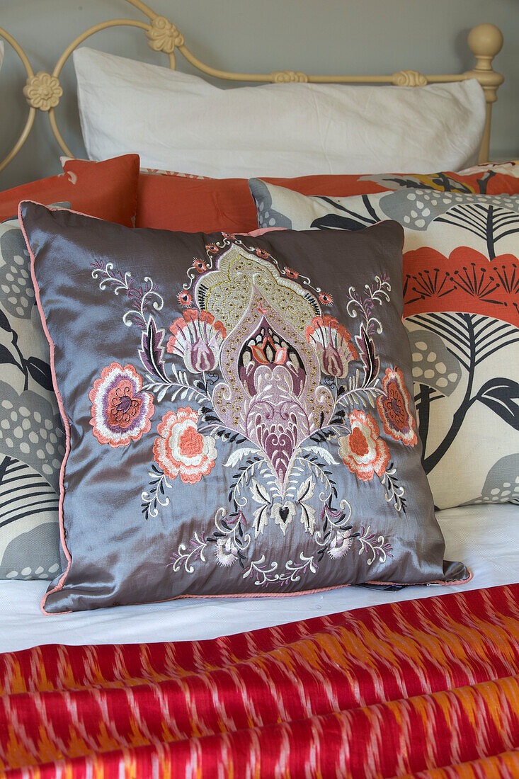 Embroidered floral cushion on wrought iron bed in London home,  England,  UK