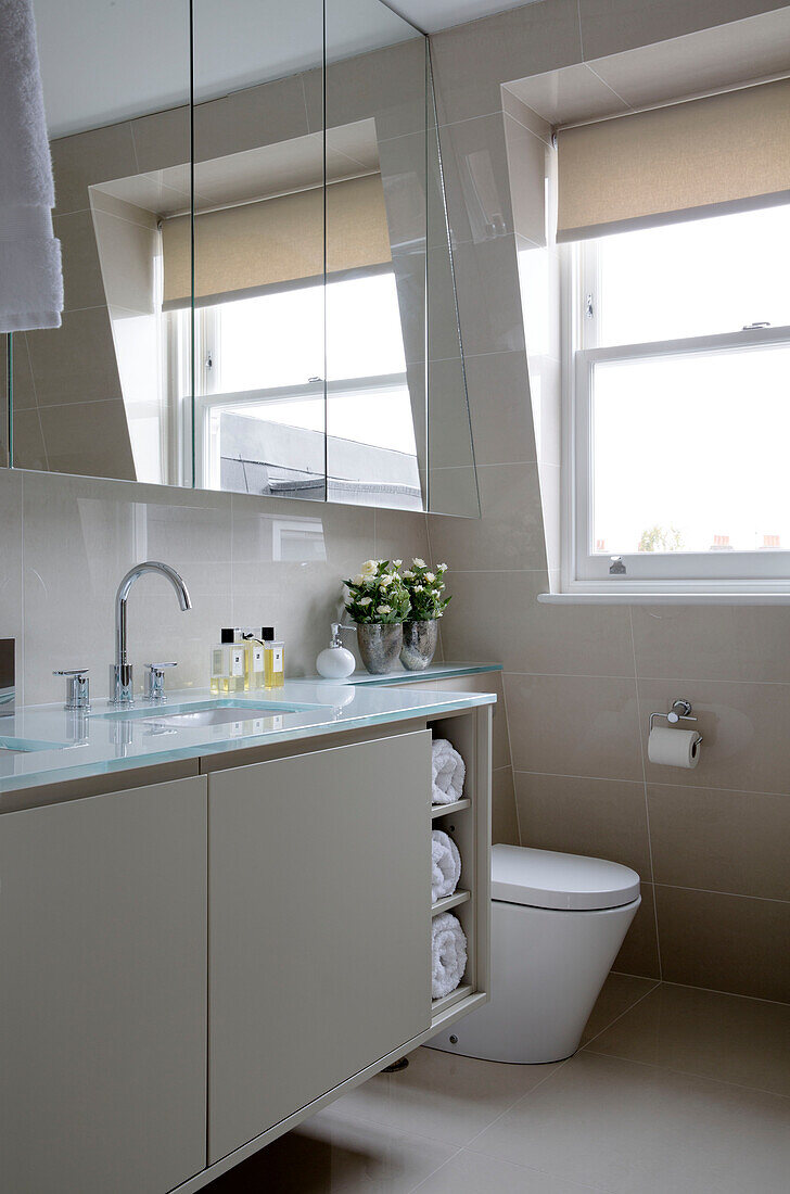 Glasabdeckung des Waschbeckens mit Spiegelschrank in einer modernen Londoner Wohnung UK