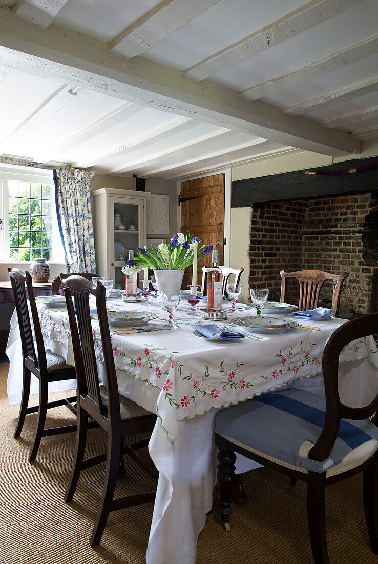 Embroidered tablecloth on dining table with dark wooden chairs in UK farmhouse
